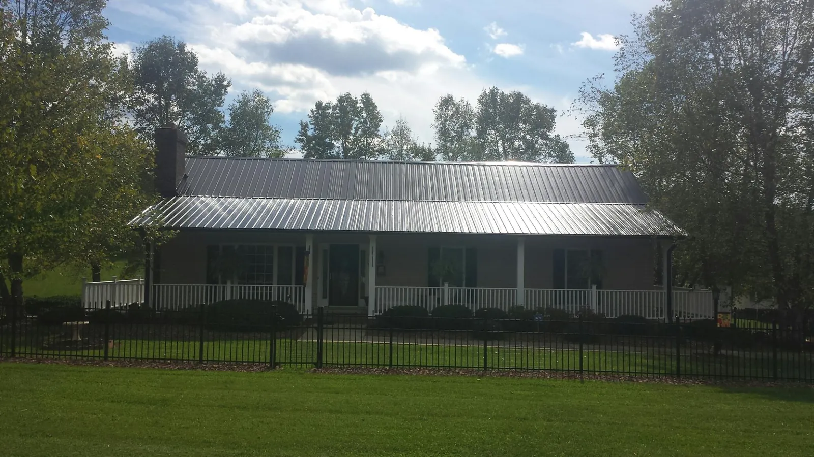 Gray metal roof on a brick ranch with a full width front porch — Gutter Guard Installation work by our crew in Manson