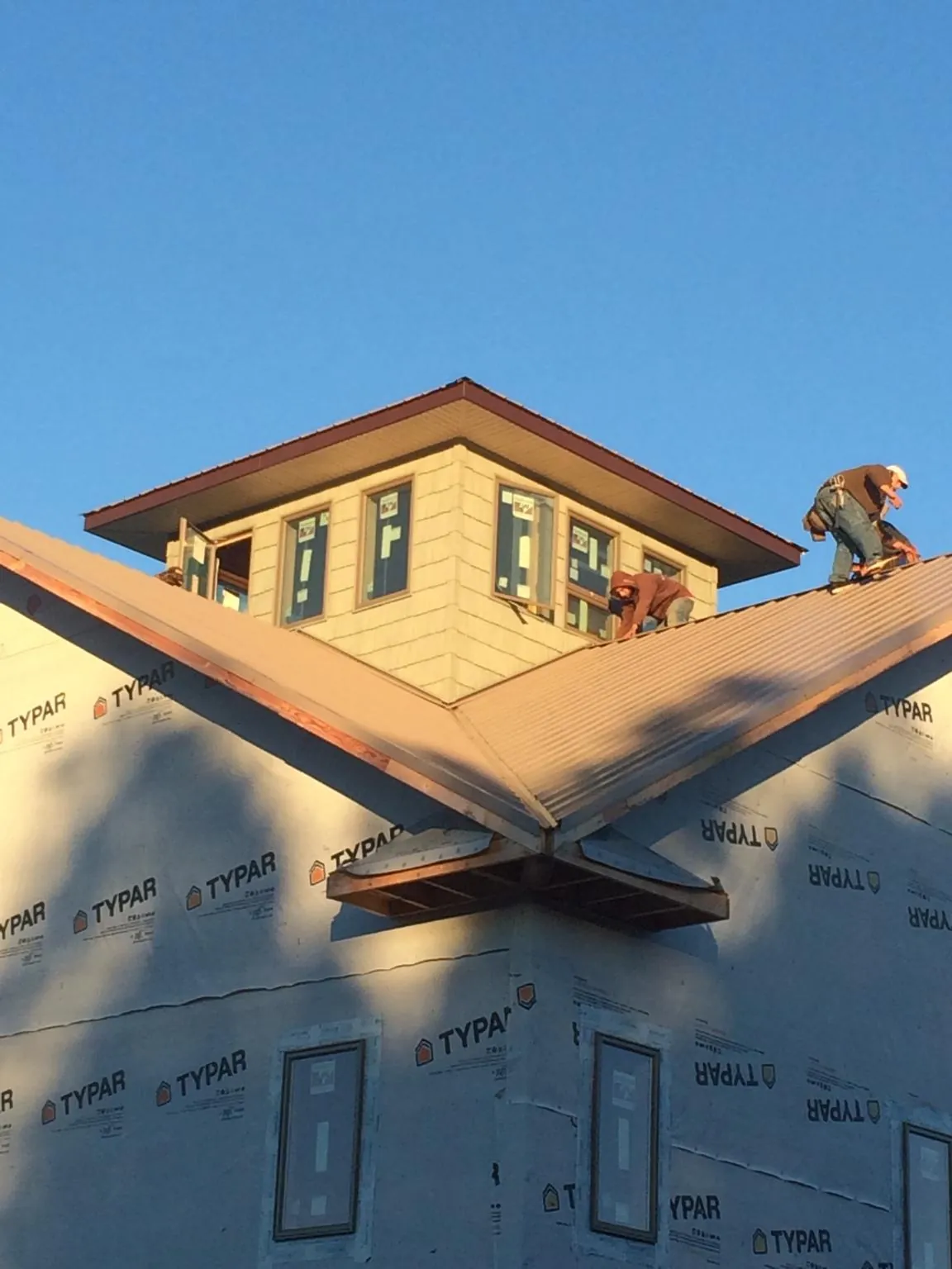 Roofers working around a rooftop cupola on a new metal roof at sunset — Roof Waterproofing in Manson by Roofing Brothers